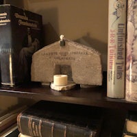 a book shelf with books and a candle on it