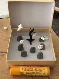 a box containing a set of figurines and a pencil