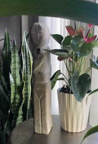 a statue of a man sitting on a table next to a plant