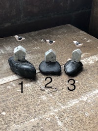 three small rocks with birds on them