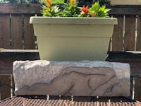 a statue of a woman laying on a bench next to a potted plant