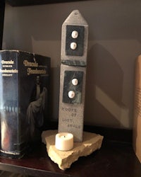 a statue of a clock on a shelf next to a book